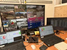A video wall of camera feeds above the graphics laptops