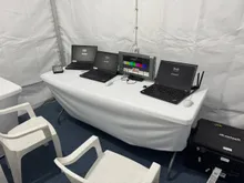 A graphics station with laptops and a test-pattern monitor in a production tent